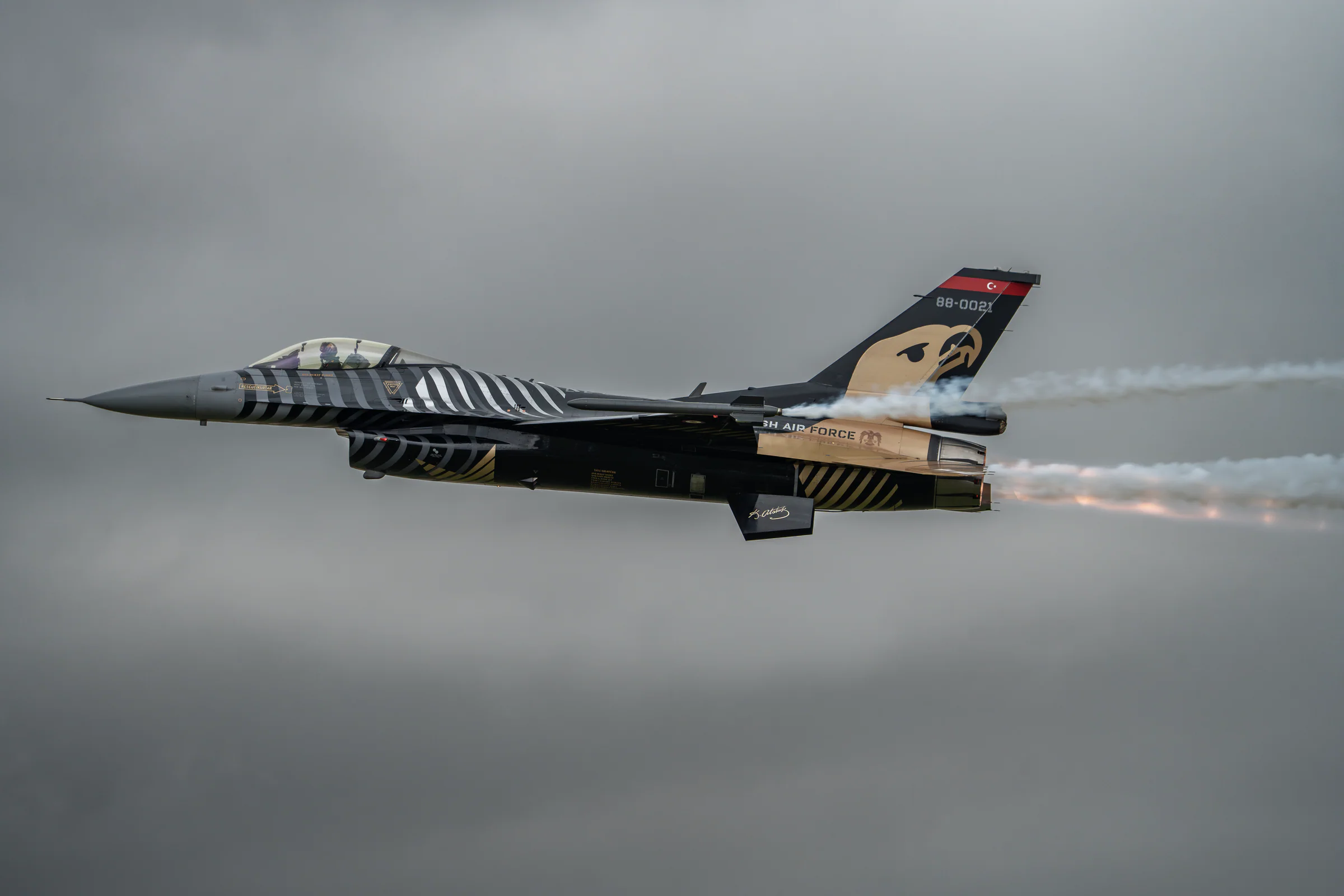A fighter aircraft in tiger livery passing with afterburner, photographed by Kieran Lim