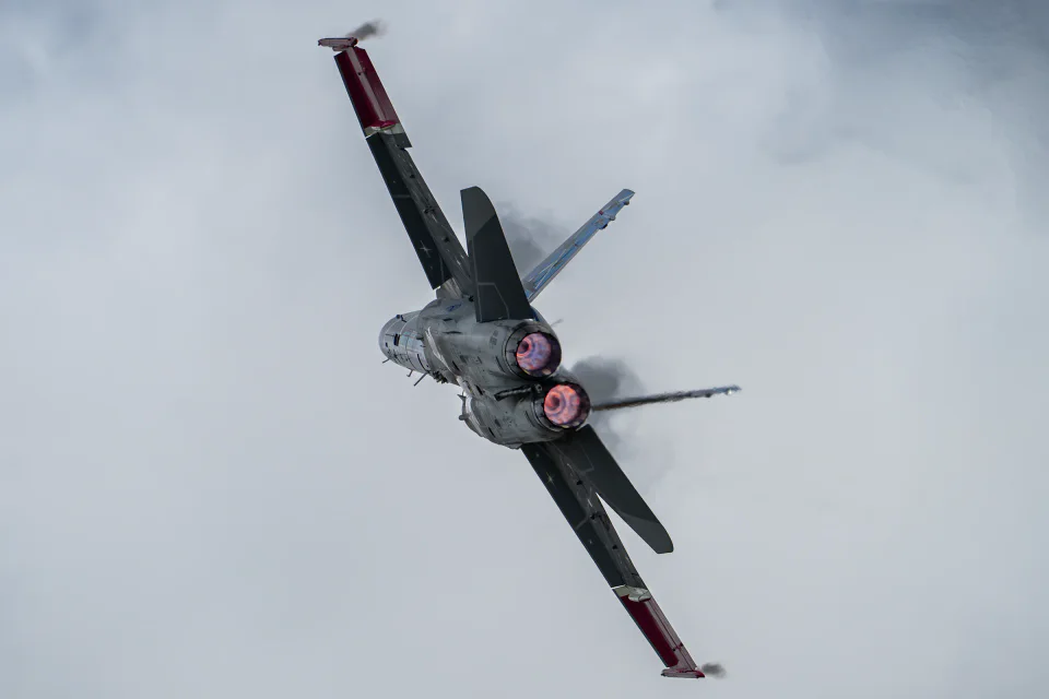 A fighter aircraft banking with afterburner visible